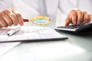 Man calculating taxes with magnifying glass in hand