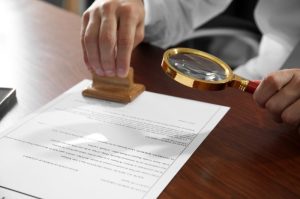 Attestator stamped on the the paper with magnifying glass in other hand