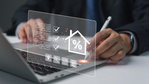 Man using laptop with holographic interface, displaying finance icons. Represents digital finance.