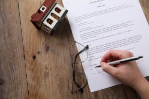 Woman signing Last Will and Testament at wooden table