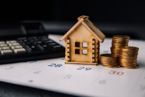 Real estate and mortgage reminder concept with wooden house, calendar, coins, and calculator 