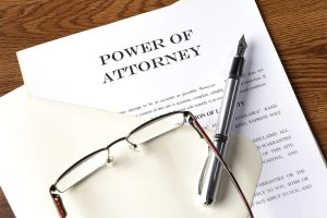 Person reviewing power of attorney documents with pen and legal paperwork on table. 