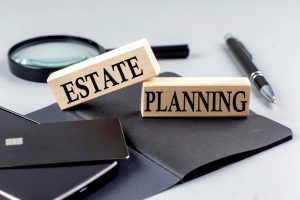 Wooden block with "ESTATE PLANNING" text on top of a black notebook, representing business concept