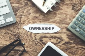 Close-up of a torn piece of paper with the word 'Ownership' printed on it, symbolizing broken or disputed ownership rights.
