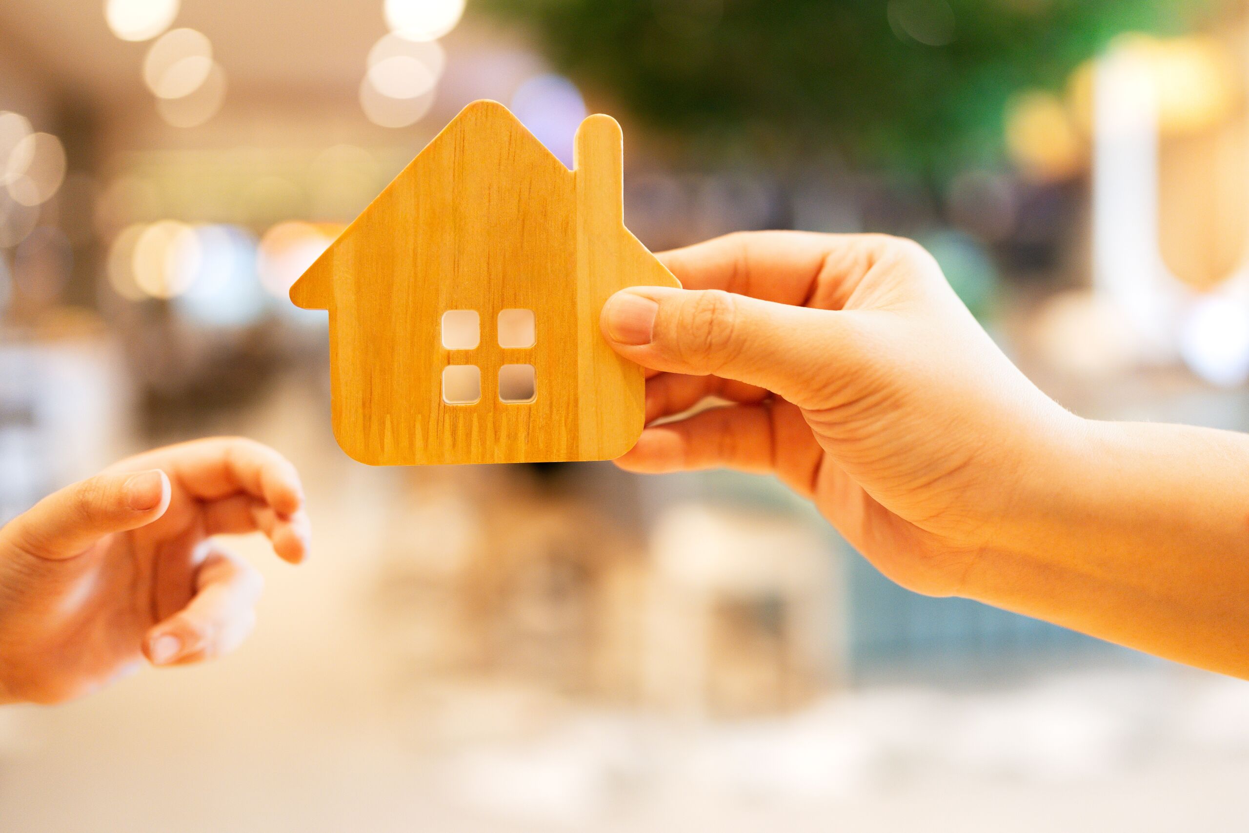 Hands holding a wooden house cutout in Florida, representing property that may transfer automatically without going through probate.