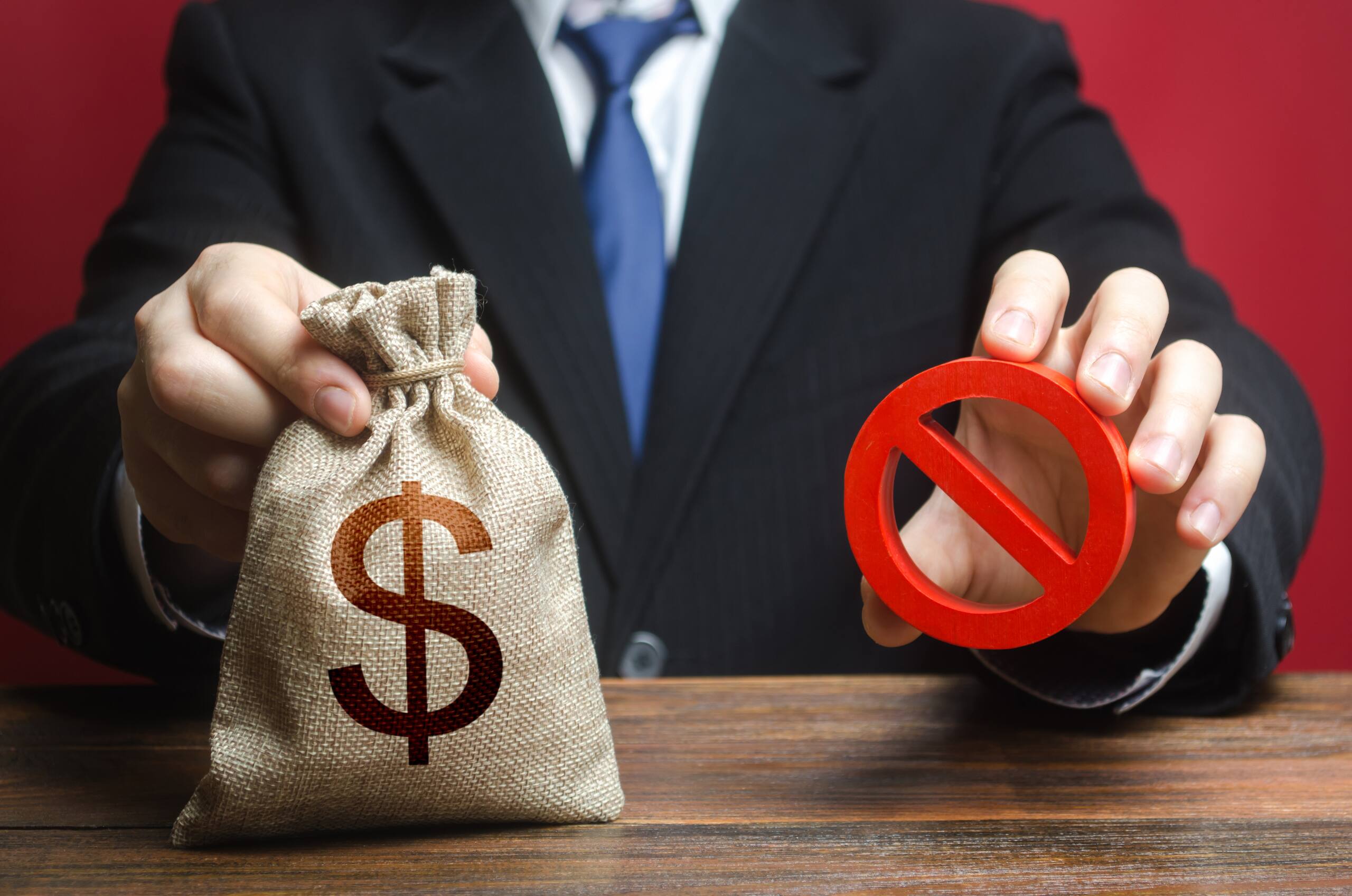 A person in a suit holding a money bag and a "no" sign, representing non-probate assets that transfer directly to beneficiaries in Florida.