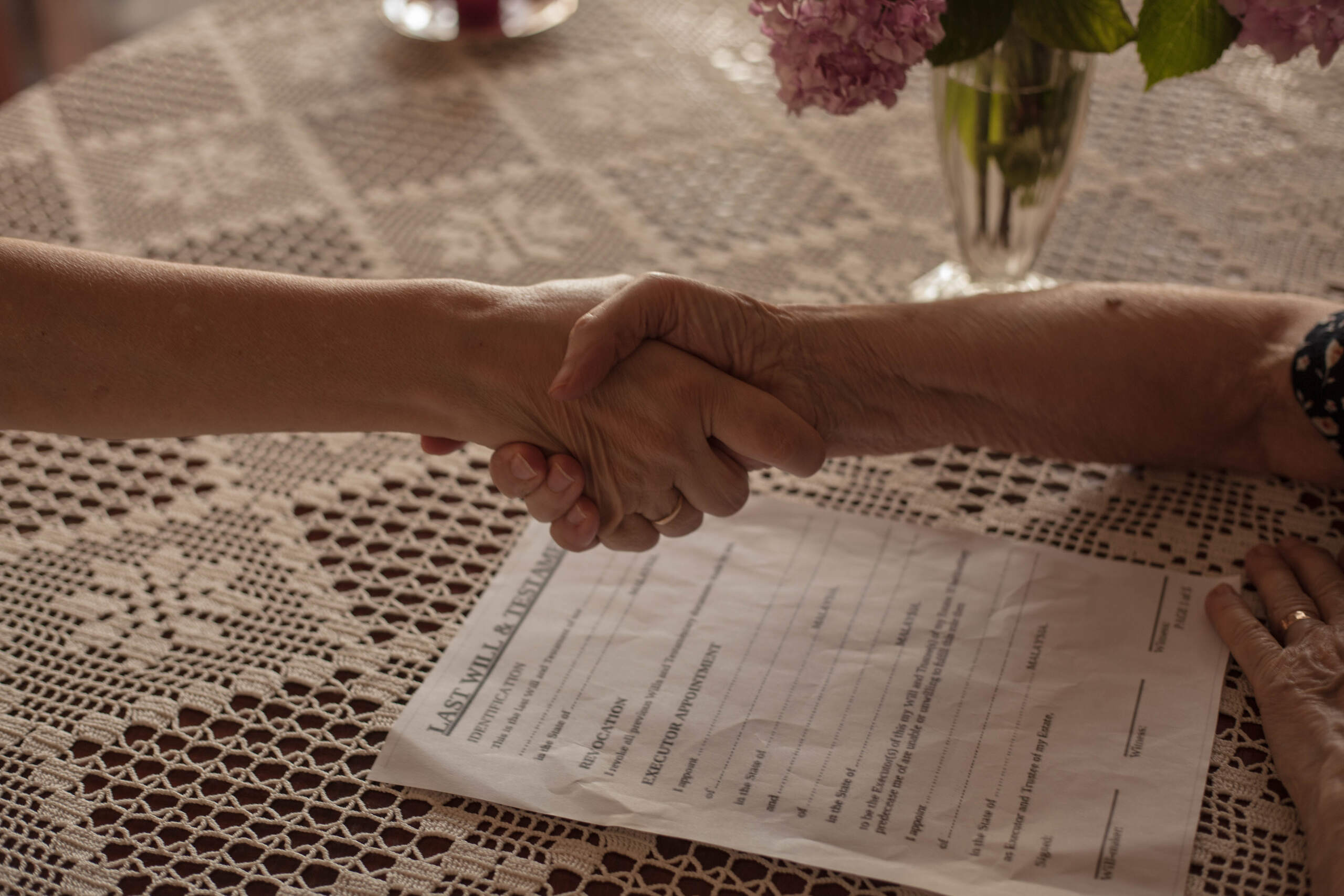 Two people shaking hands over estate documents to answer how long does trust administration take in Florida.