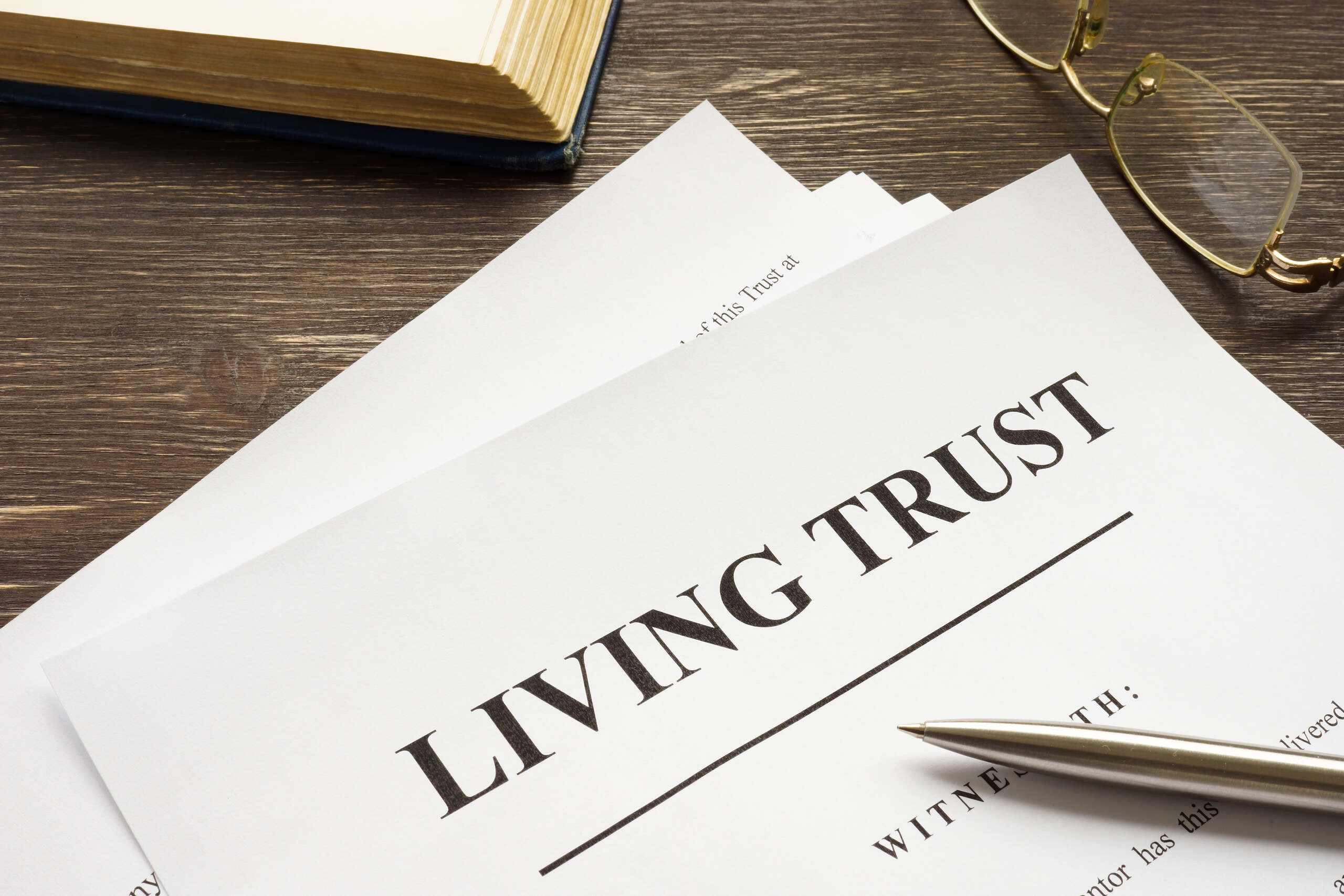 Living trust document with a pen and glasses outlining how long does trust administration take in Florida.