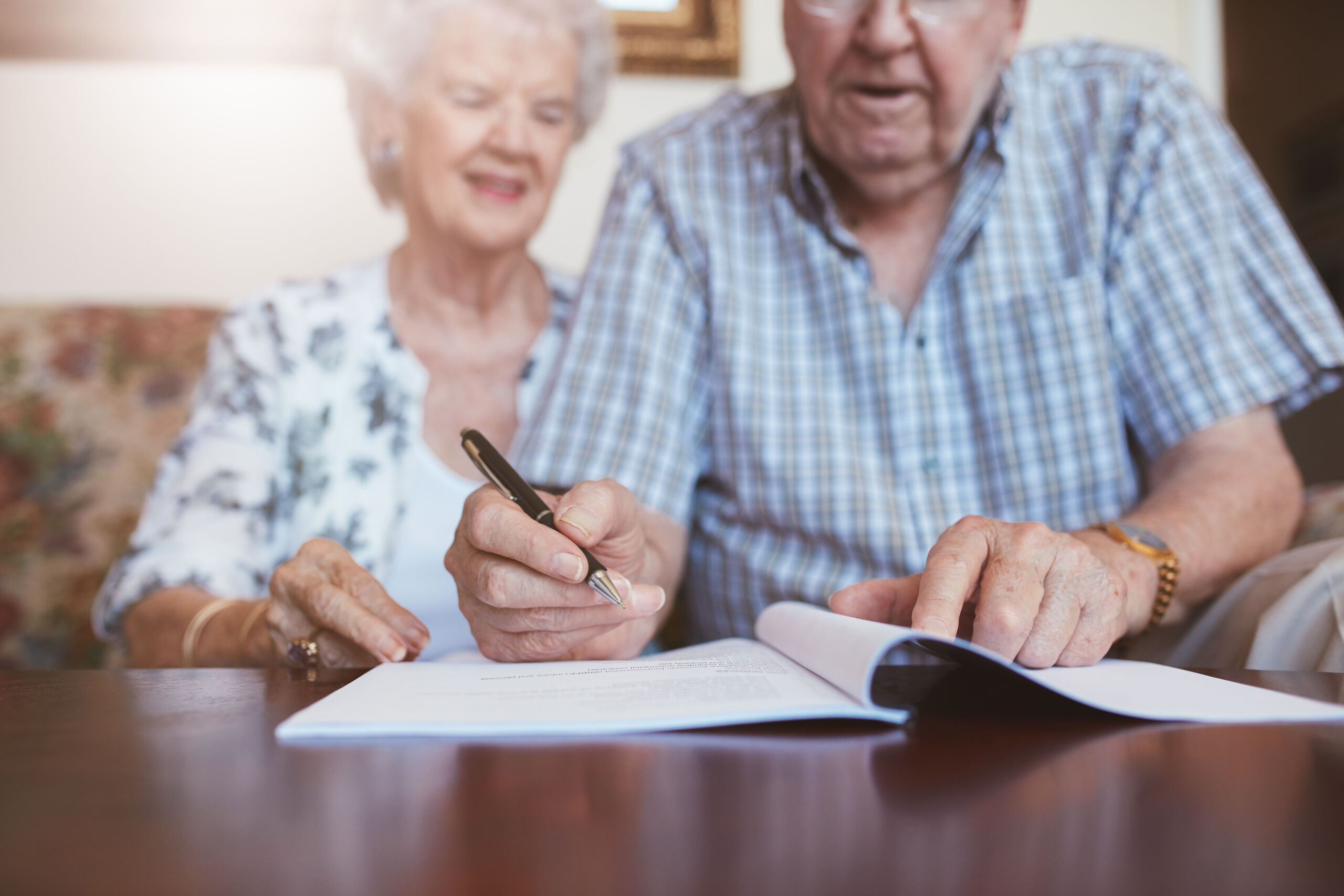 Senior couple signing legal documents to understand living will vs. healthcare surrogate and why Coral Gables residents need both.